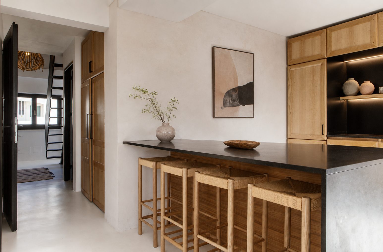 Cozinha com bancada escura e banquetas de madeira