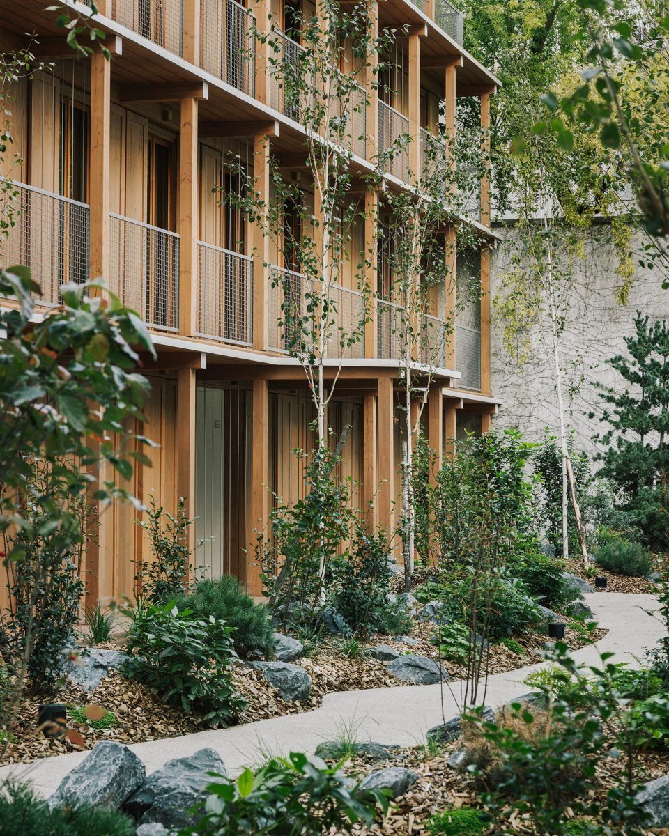 Fachada do Wood Collective com brises de madeira e jardim
